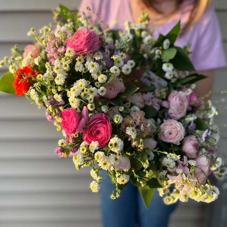 bouquets held in hand with white purple and pink flowers